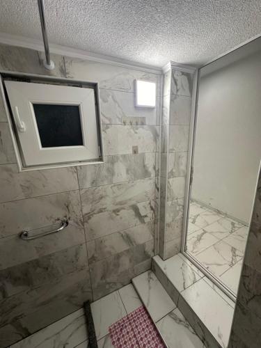 gvero apartment’s في بريليب: حمام مع دش وتلفزيون على الحائط