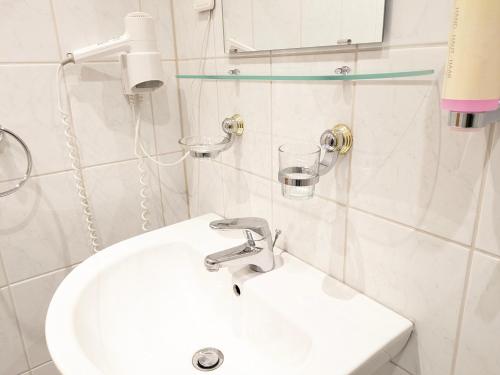 biała łazienka z umywalką i szkłem w obiekcie Landhaus Ellernkrug Hotel w mieście Lage
