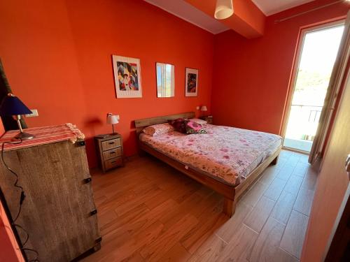 sypialnia z pomarańczowymi ścianami, łóżkiem i oknem w obiekcie Casa Cinque Colori w mieście Rodi