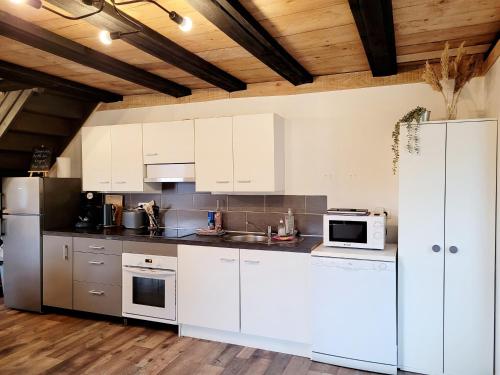 une cuisine avec des armoires blanches et des appareils électroménagers blancs dans l'établissement Cottage le Ni-La, à Fresse-sur-Moselle