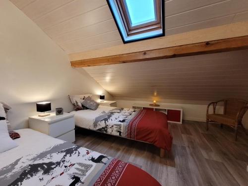 a attic bedroom with two beds and a window at Cottage le Ni-La in Fresse-sur-Moselle