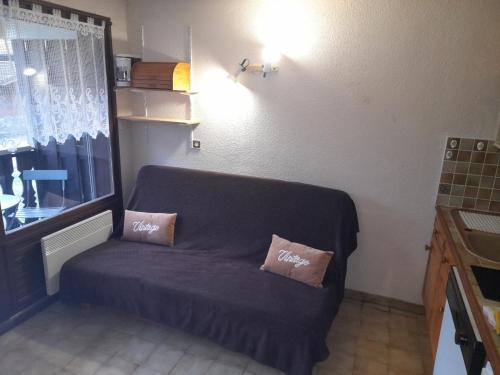 un divano in camera con due cuscini sopra di Le chalet des neiges 3 est au calme situé à 5 mn à pied du centre juste à côté du terrain de foot est composé canapé convertible et 3 lits supperposés parking privé sur place et arrêt navette gratuite à 30 m a Les Carroz d'Araches