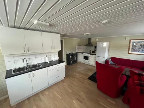 een keuken met witte kasten en een rode bank bij Welcome Inn Hotel Lyngskroa in Oteren