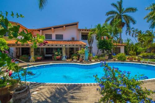 a swimming pool in front of a house with palm trees at Casa Virgilios B&B in Nuevo Vallarta