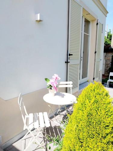 a white table and chairs on a patio with flowers at BEE HOME in Luni