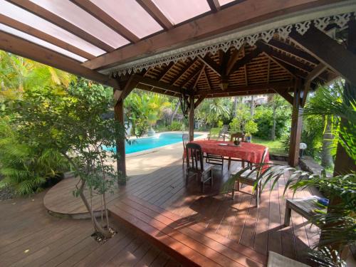 une pergola en bois avec une table et des chaises sur une terrasse dans l'établissement Case papangue, à Saint-Paul
