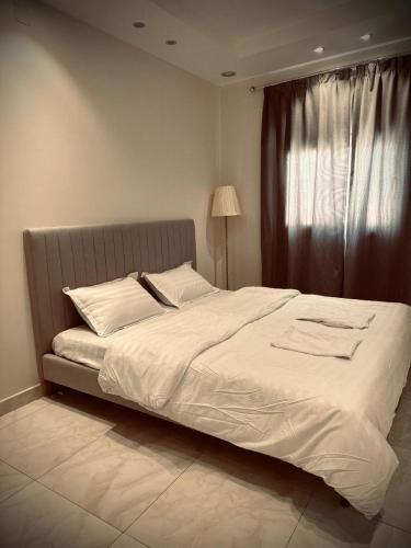 una camera da letto con un grande letto bianco e una finestra di ابها a Abalah