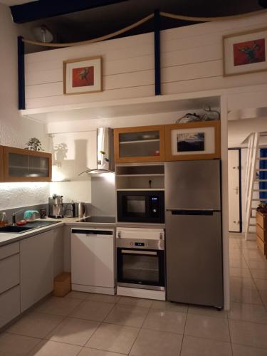 une cuisine avec des appareils en acier inoxydable et des armoires en bois dans l'établissement Le duplex panoramic sur Mer et Lido, à Sète