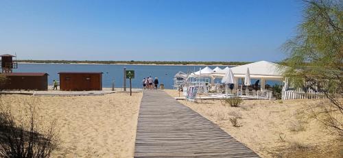 a wooden boardwalk leading to a beach with tents at Apartamento Pleamar in El Rompido
