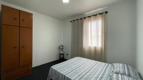 een slaapkamer met een bed, een dressoir en een raam bij desativado in São Vicente