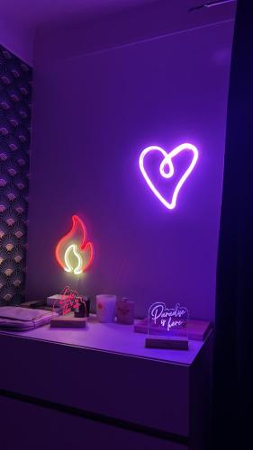 une chambre violette avec des panneaux de néon sur le mur dans l'établissement Havre de paix proche épreuves JO 2024, à Vaires-sur-Marne