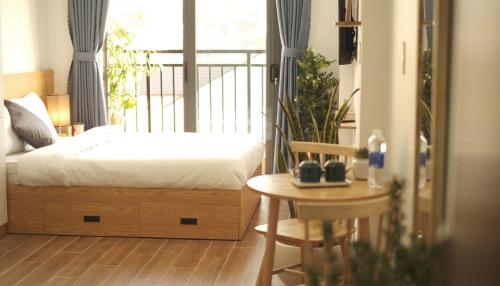 a bedroom with a bed and a table and a window at Kōzē Mini Apartment in Da Lat