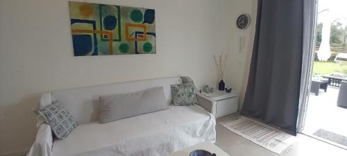 uma sala de estar com um sofá branco e um quadro em Mirasole Holiday House em Leggiuno