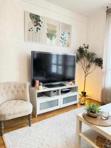 ein Wohnzimmer mit einem Flachbild-TV auf einem weißen Entertainment-Center in der Unterkunft Duplex cosy 53m2 pour les JO in Viroflay