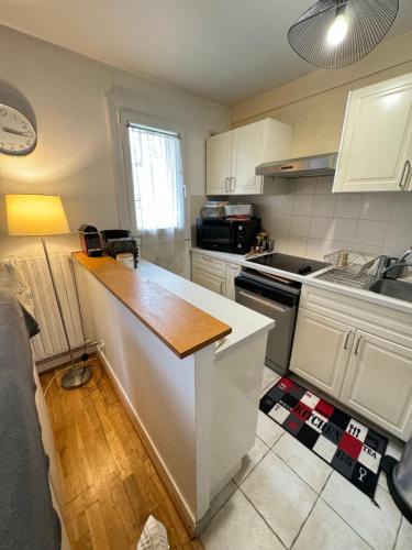 une cuisine avec des armoires blanches et un comptoir dans l'établissement Duplex cosy 53m2 pour les JO, à Viroflay