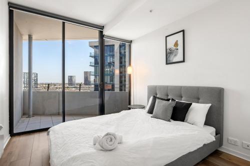 1 dormitorio con 1 cama blanca grande y balcón en Sea View, Gym & Pool, 2 bedrooms 2 bathrooms en Melbourne