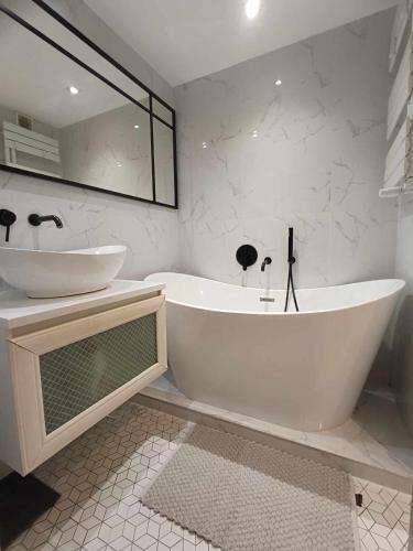 a white bathroom with a tub and a sink at DWUPOKOJOWY APARTAMENT 51 m2 in Łódź