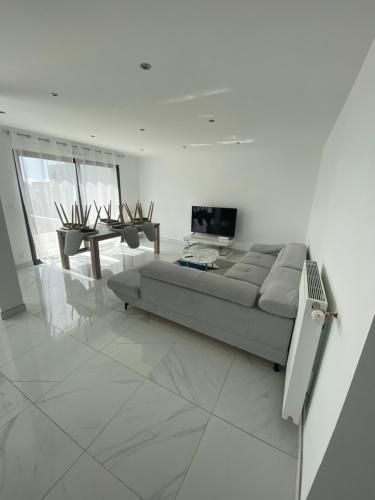 a white living room with a couch and a television at Maison vue mer st anne du Portzic in Brest