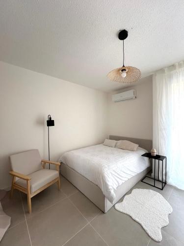 una camera bianca con un letto e una sedia di Appartement Balaruc les bains a Balaruc-les-Bains