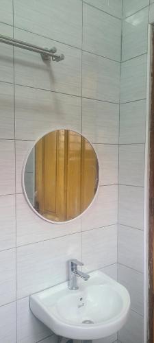 baño con lavabo y espejo en la pared en Solace Guest House, en Entebbe