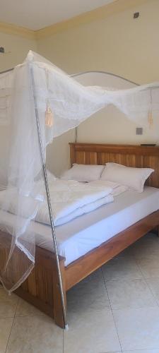 Una cama con mosquitera encima. en Solace Guest House, en Entebbe
