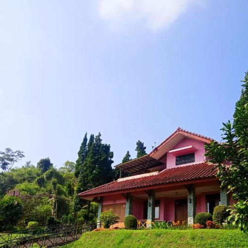 ein rosa Haus auf einem Hügel mit Bäumen im Hintergrund in der Unterkunft Villa Ciater 3 in Cicadas
