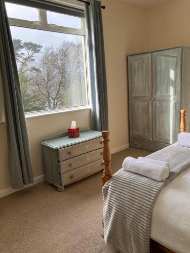 1 dormitorio con cama, ventana y vestidor en Dunholm Cottage, en Skelmorlie