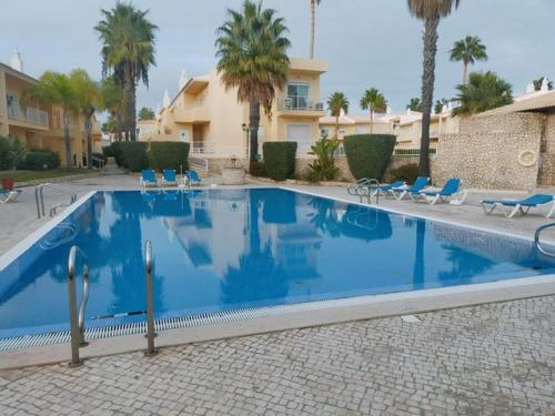 a large blue swimming pool with chairs and a building at Holidays in Albufeira - Algarve in Albufeira