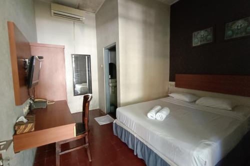 ein Hotelzimmer mit einem Bett und einem TV in der Unterkunft Ndalem Mantrigawen in Yogyakarta