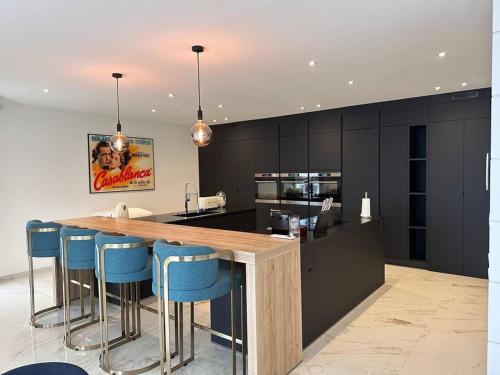 une cuisine avec comptoir et tabourets de bar bleus dans l'établissement penthouse vue mer Ajaccio, à Ajaccio