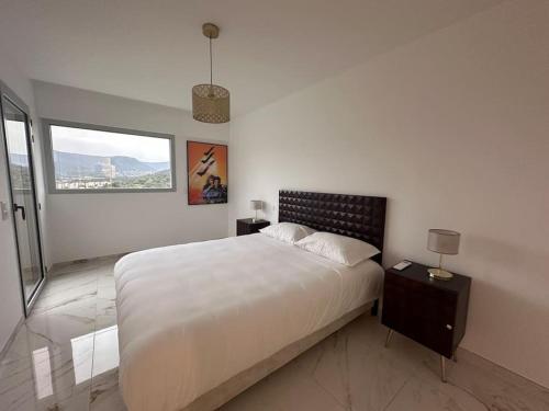 um quarto branco com uma cama grande e uma janela em penthouse vue mer Ajaccio em Ajaccio