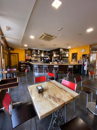 un restaurante con mesa y sillas y un bar en Pensión Pousada Chiquitin, en Melide