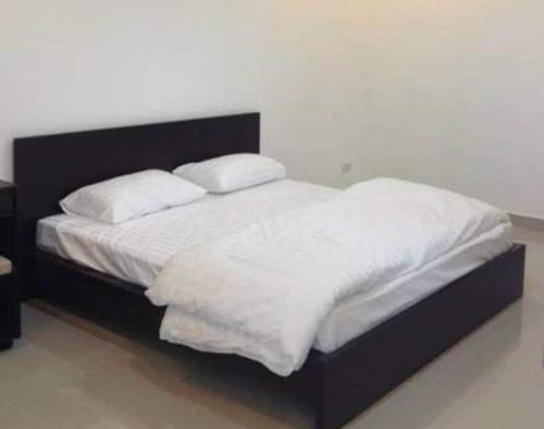 um quarto com uma cama com lençóis brancos e almofadas em The Room Nangrong em Nang Rong