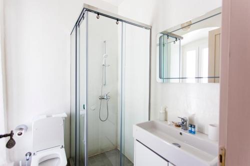 a white bathroom with a shower and a sink at Militiko in Himare