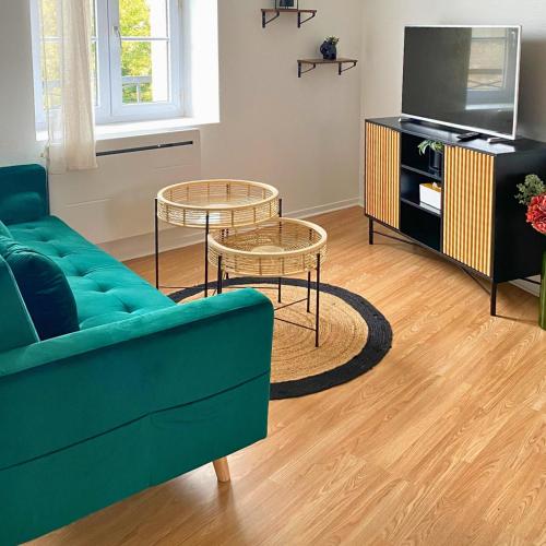 a living room with a green couch and two tables at Studio Cosy et Lumineux à Etampes in Étampes