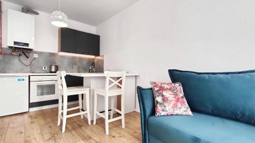 a living room with a blue couch and a kitchen at APARTAMENTY Charzykowy in Charzykowy
