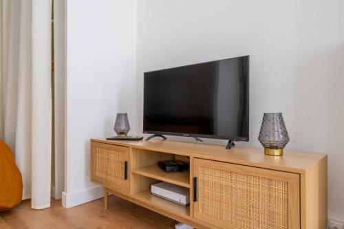 un téléviseur à écran plat posé sur un centre de divertissement en bois dans l'établissement T1 Cocooning proche métro Baille, à Marseille