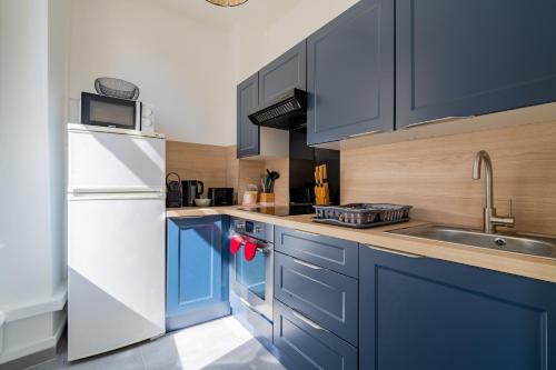 La cuisine est équipée de placards bleus et d'un réfrigérateur blanc. dans l'établissement T1 Cocooning proche métro Baille, à Marseille