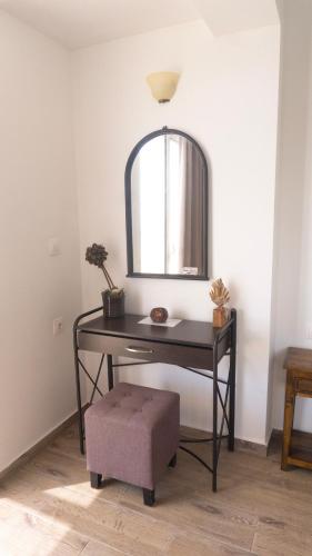 a table with a stool and a mirror on a wall at Seaside Studios Kirania in Kiotari