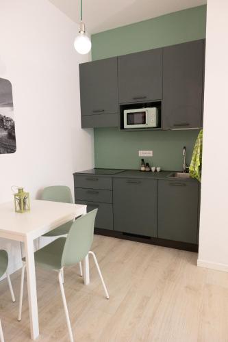 a kitchen with gray cabinets and a white table and chairs at Cà Cianfer in Bergamo