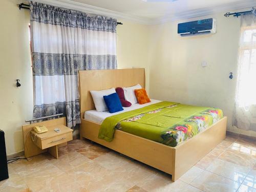 1 dormitorio con 1 cama con almohadas coloridas en Legends Castle Suites, en Gwarinpa