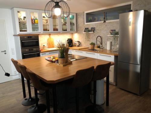 a kitchen with a wooden table and a refrigerator at Stylisches Maybach Appartement mit Terrasse für 5-7 Personen, 5 Betten, große Kochinsel, Homeoffice mit 250Mbit WLAN in Aidlingen