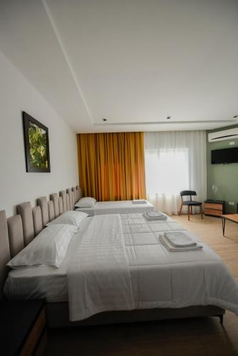 a bedroom with a large bed with white sheets at Hotel Blini in Shkodër