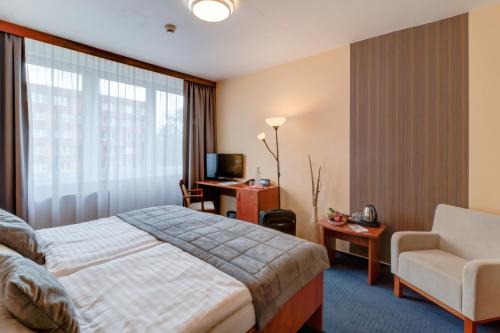 um quarto de hotel com uma cama e uma cadeira em LC - Hotel Ostrava em Ostrava