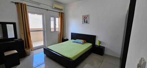 een kleine slaapkamer met een bed en een raam bij Ollier Plaza Apartments in Port Louis