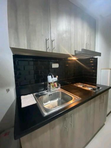 - une cuisine avec un évier et un comptoir noir dans l'établissement S residences Pasay , near Mall of Asia, à Manille