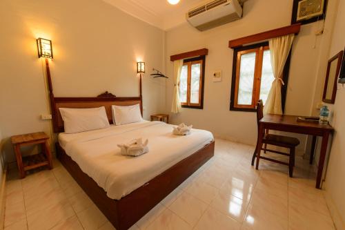 Schlafzimmer mit einem großen Bett, einem Schreibtisch und einem Tisch in der Unterkunft Sabaidee Guesthouse in Luang Prabang