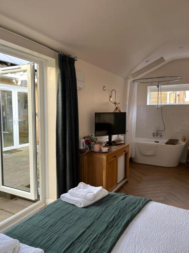 a bedroom with a bed and a tv and a tub at The chalet in Chandlers Ford