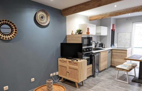 une cuisine avec une télévision à écran plat sur une armoire en bois dans l'établissement Sea, sun et vignes, à Nissan-lez-Enserune