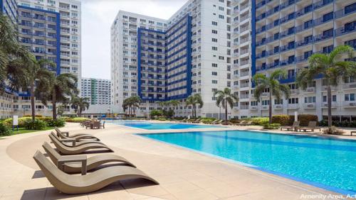 SEA Residences in Pasay near Mall of Asia 2BR and 1BR في مانيلا: مسبح مع كراسي جلوس الكراسي امام مباني طويلة